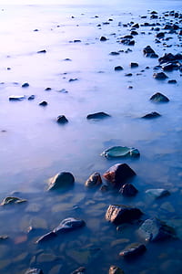 black rocks on body of water at daytime thumbnail