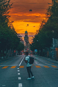 man standing on gray concrete road taken at sunset thumbnail