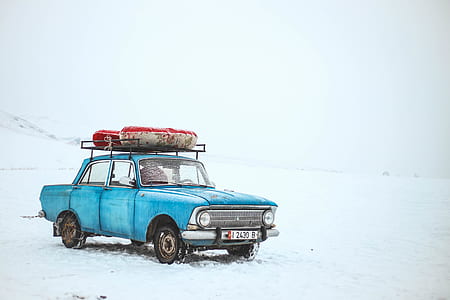classic blue sedan on snowy field thumbnail