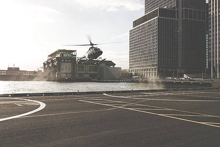grayscale photo of helicopter about to land near buildings thumbnail