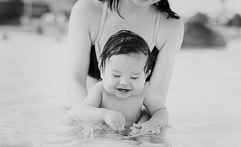 woman carrying baby on in body of water thumbnail