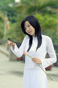 woman wearing white long-sleeved shirt holding black bird and pink tulip flower during daytime thumbnail