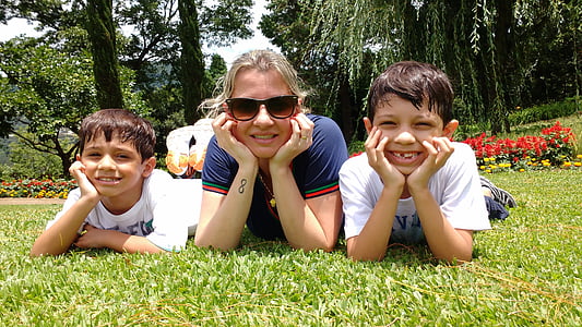 woman lying on grass beside two boys during daytime thumbnail