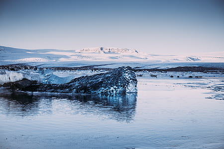photo of snow-covered island under cloudy blue sky thumbnail