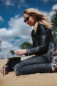 Young woman wearing a leather jacket and sunglasses on the beach thumbnail