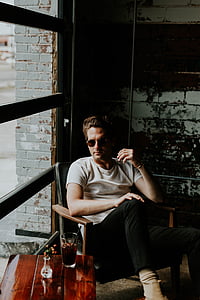 man sitting on chair beside glass window thumbnail