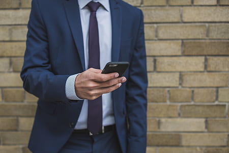 man wearing blue suit jacket holding smartphone thumbnail