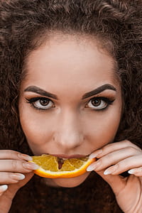 photo of woman eating sliced orange fruit thumbnail