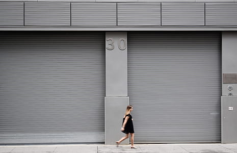 woman walking near gray metal wall thumbnail