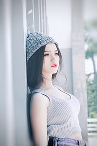 woman wearing gray crop top leaning on gray wall in selective focus photo thumbnail