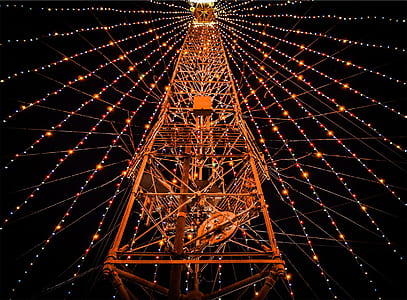 low-angle photography of red metal tower surrounded with turned on assorted-color string lights at night thumbnail