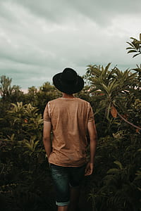 man standing near green leaf plants during daytime thumbnail