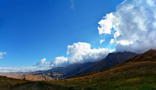 brown mountain under white clouds and blue sky at daytime thumbnail