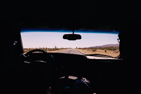 silhouette photography of vehicle rear-view mirror speeding on concrete road under clear blue sky thumbnail