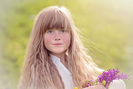 girl in white top holding purple flowers thumbnail