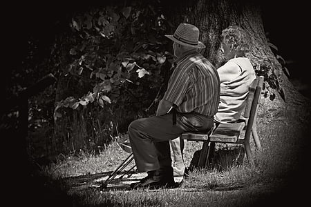 grayscaled photo of man and woman sitting on wooden outdoor bench thumbnail