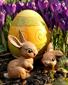 two rabbit figurines near yellow decorative egg and purple flowers during day thumbnail