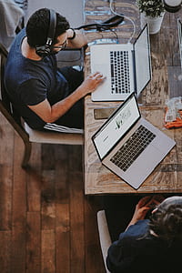man sitting on brown wooden chair touching MacBook Pro thumbnail