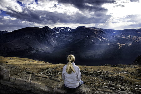woman sitting on rock while looking to mountains thumbnail
