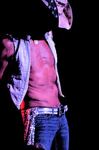 man wearing button-up vest; cowboy hat; and blue denim bottoms thumbnail