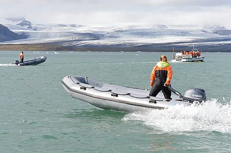 man in black and orange suit riding on boat during daytime thumbnail