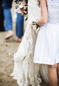 Girl in White and Blue Dress Holding Wedding Dress of Woman thumbnail