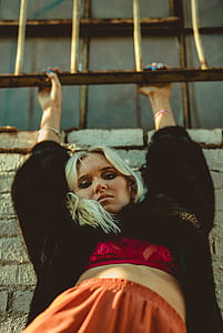 woman hanging while leaning on wall during daytime thumbnail