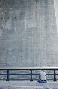 man sitting on fence facing building thumbnail