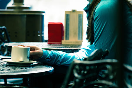 Person in Green Long-sleeved Top Sitting on Chair White Holding White Ceramic Mug thumbnail