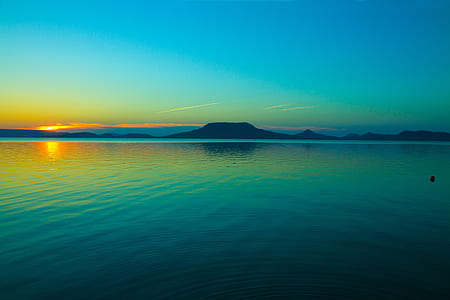 blue body of water and silhouette mountains thumbnail