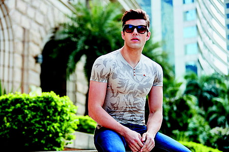 man sitting wearing blue bottoms and grey floral shirt thumbnail