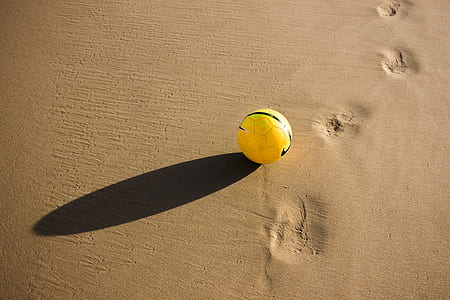 yellow soccer ball on gray sand during daytime thumbnail