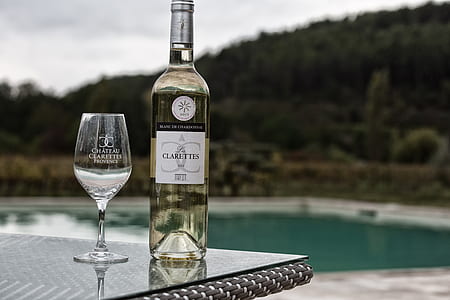 wine glass beside wine bottle on table near pool thumbnail