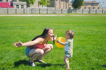 girl playing with toddler on green grass thumbnail