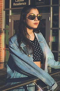 woman wearing hippie sunglasses while holding on fence thumbnail