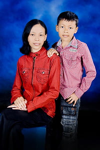 boy standing beside woman sitting on blue stool thumbnail