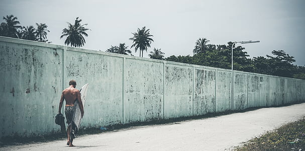 man carrying a white surfboard thumbnail