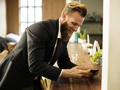 man in black suit leaning on brown wooden table thumbnail