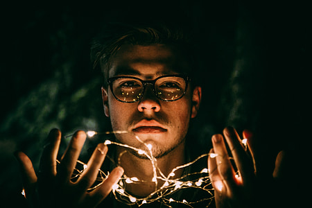 man with string lights on his hands low light photography during nighttime thumbnail