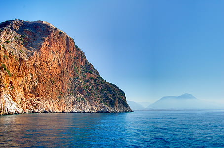 panoramic photography of hill and sea under blue sky thumbnail