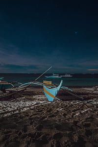 white and brown boat on brown sand beside seashore during nigttime thumbnail