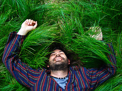 man in multicolored top lying on green grass field thumbnail