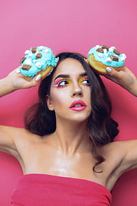 Woman in Red Tube Top Holding Two Doughnuts thumbnail