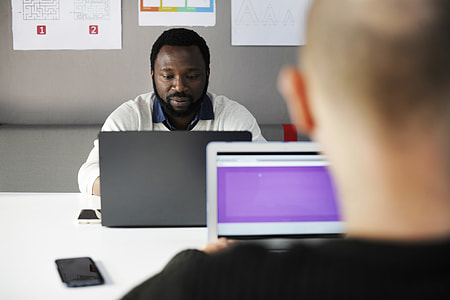 two person facing each other while using laptop computer thumbnail
