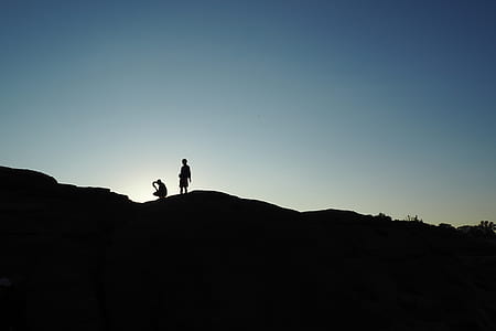 silhouette of two persons standing on mountain peak thumbnail