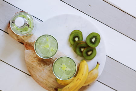 sliced kiwi fruits, unpeeled bananas, and three cups with beverages thumbnail