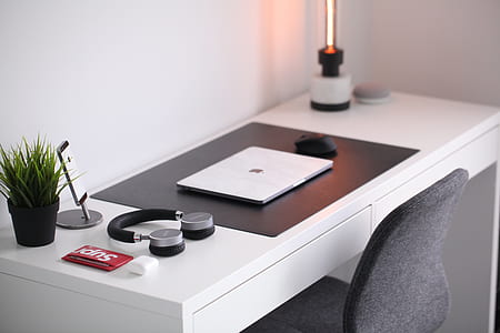 MacBook beside on-ear wireless headphones on wooden desk thumbnail