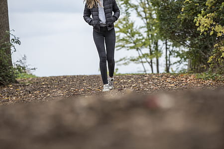 Woman in Black Leggings While Walking on Brown Road thumbnail
