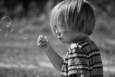 grayscale photograph of toddler blowing bobbles thumbnail