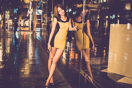 woman leaning on clear glass wall during nighttime thumbnail
